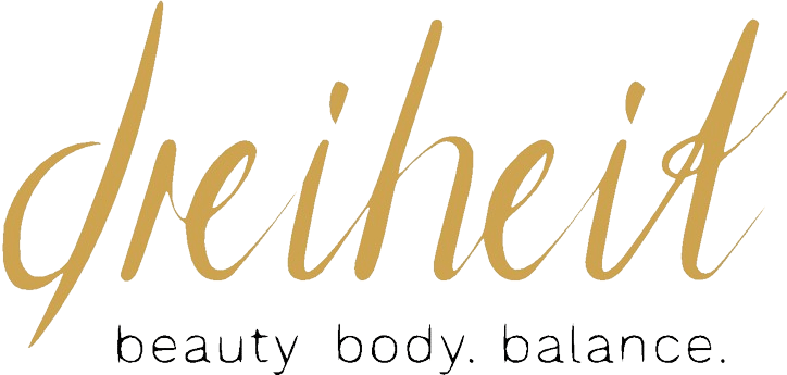 Das Logo zeigt den goldenen Schriftzug „Dreiheit“ mit dem Slogan „beauty body. balance.“ auf grünem Hintergrund.